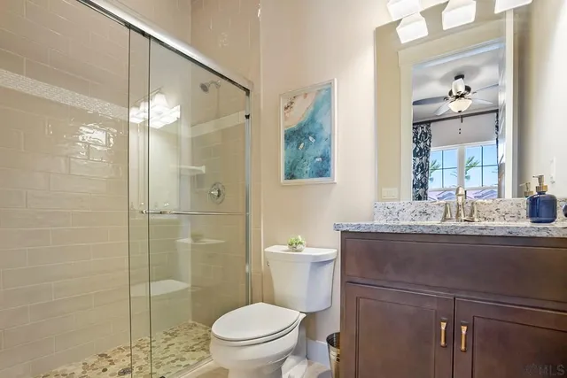 a bathroom with a granite countertop sink a toilet and shower