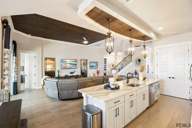 a large white kitchen with a stove a sink dishwasher and a dining table with wooden floor