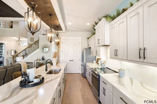 a kitchen with stainless steel appliances granite countertop a sink dishwasher stove and white cabinets with wooden floor