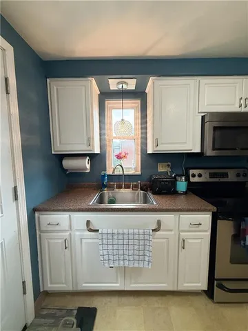 a kitchen with stainless steel appliances granite countertop a stove a sink and white cabinets