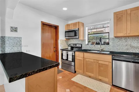 a kitchen with granite countertop a refrigerator stove top oven and sink