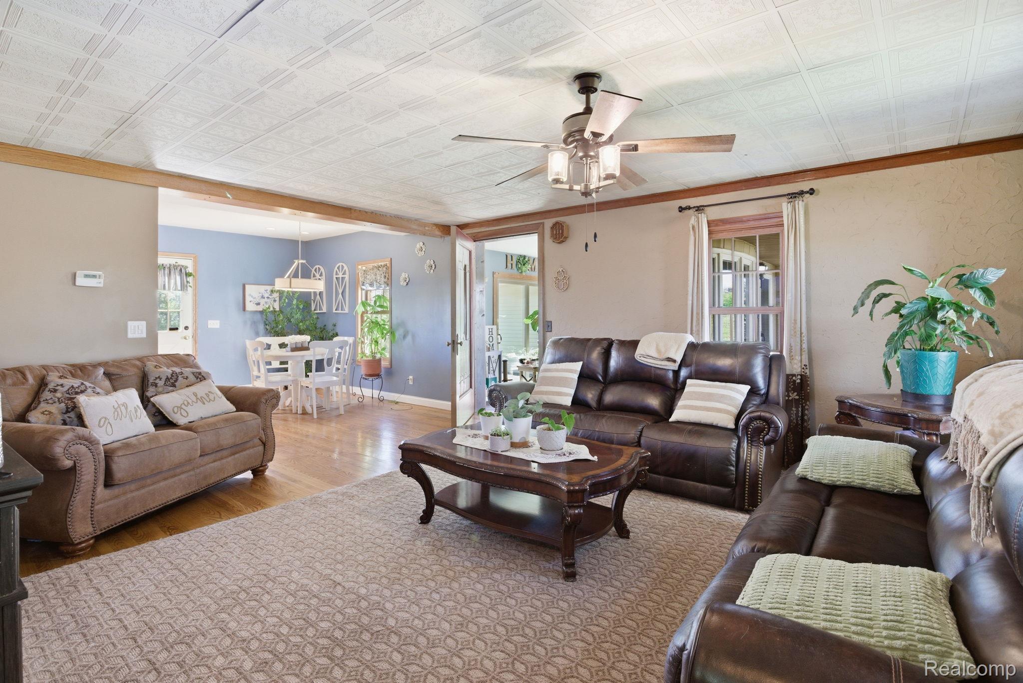 14104 Carleton West Road Carleton, MI 48117 - Photo 11 of 58 Living room featuring wood finished floors, a ceiling fan, and an ornate ceiling