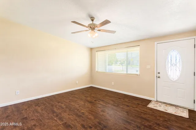 a view of an empty room with window and wooden floor
