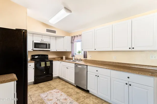 a kitchen with granite countertop white cabinets and stainless steel appliances