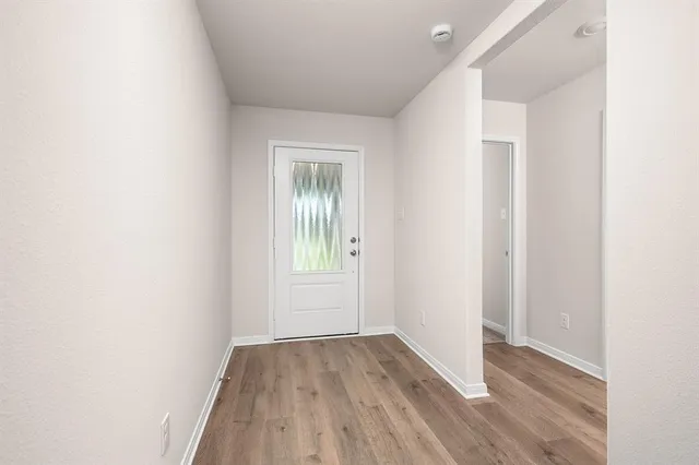 a view of an empty room with wooden floor and a window