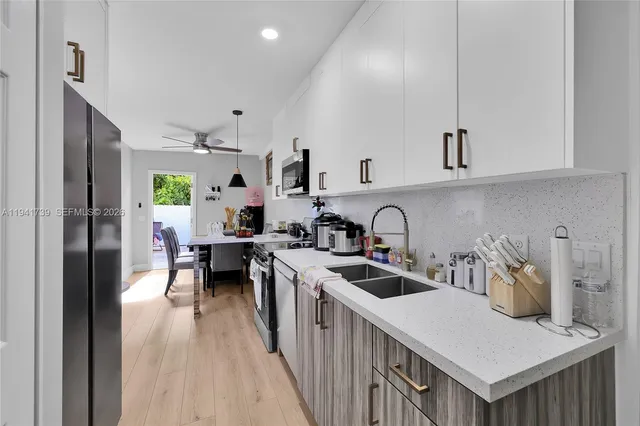 a kitchen with stainless steel appliances granite countertop a stove top oven a sink dishwasher and white cabinets with wooden floor