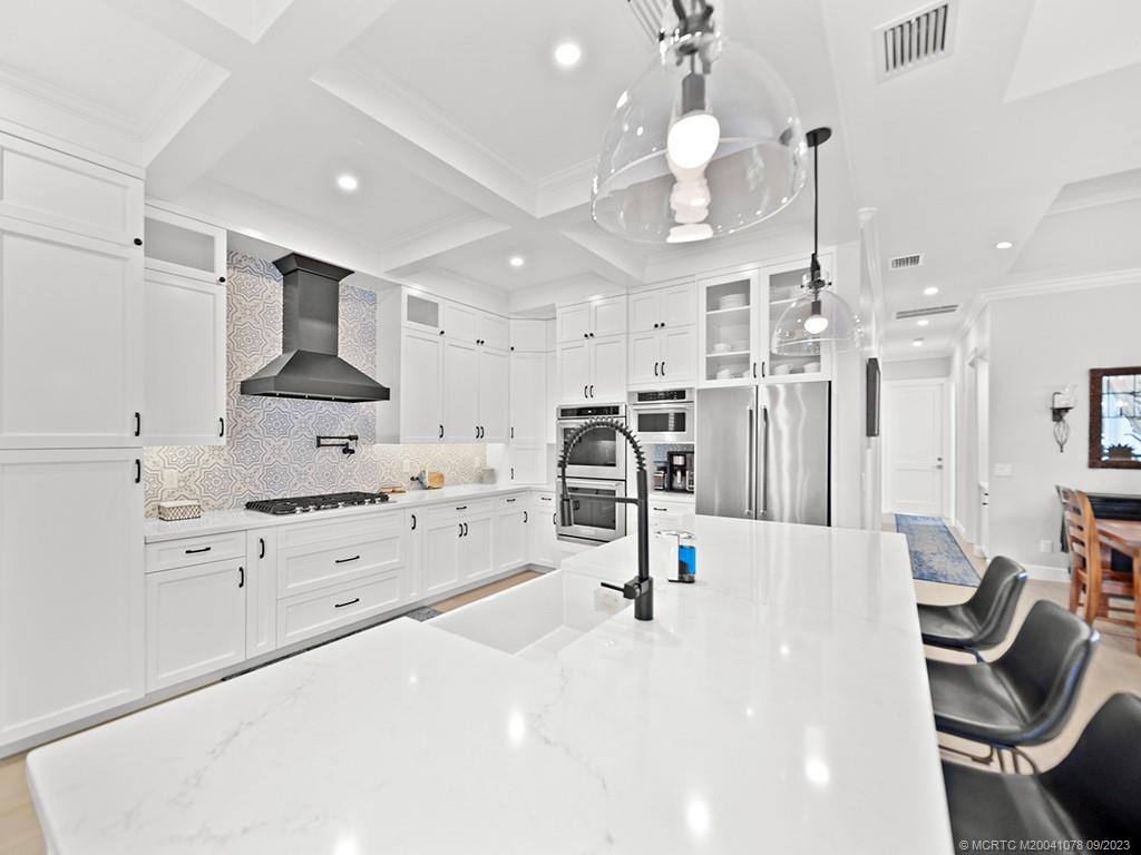 5714 Southeast Horseshoe Point Road Stuart, FL 34997 - Photo 24 of 83 a large white kitchen with lots of counter space and chandelier