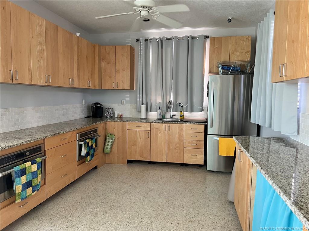 5714 Southeast Horseshoe Point Road Stuart, FL 34997 - Photo 77 of 83 a kitchen with stainless steel appliances granite countertop a stove a sink and a refrigerator