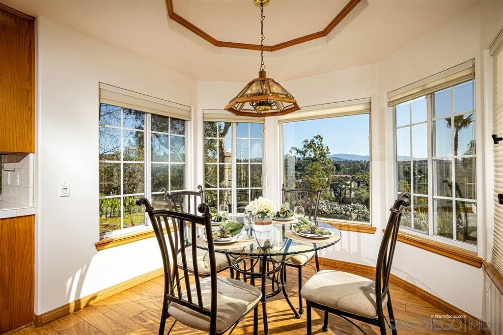 1237 Live Oak Park Road South Fallbrook, CA 92028 - Photo 9 of 25 a dining room with wooden floor a chandelier a glass table and chairs