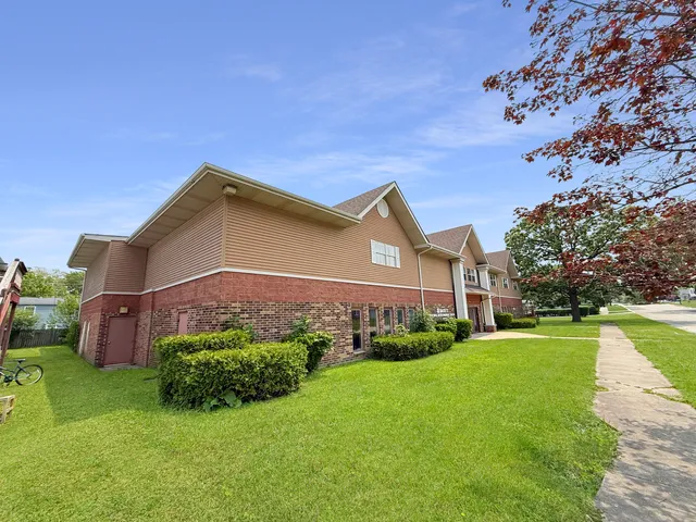 a view of a house with a big yard potted plants and a large tree