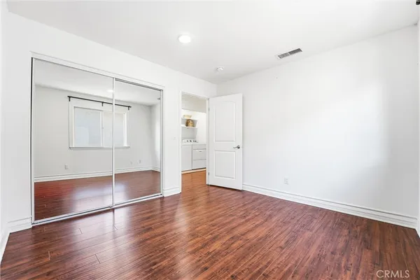 an empty room with wooden floor and mirror