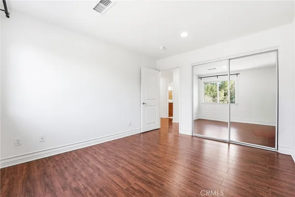 an empty room with wooden floor and natural light