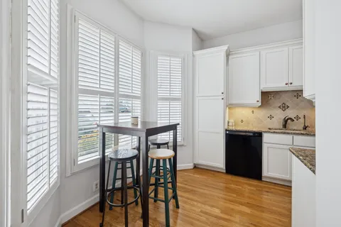 a kitchen with stainless steel appliances granite countertop a stove a refrigerator a dining table and chairs with wooden floor