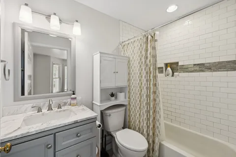 a bathroom with a granite countertop sink toilet a mirror a shower and a bathtub