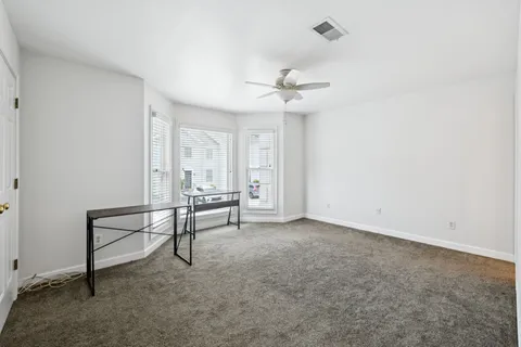 an empty room with windows and fan