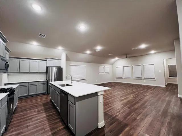 a large kitchen with kitchen island a sink dishwasher a refrigerator and white cabinets