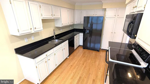 a kitchen with stainless steel appliances a refrigerator a sink and wooden cabinets