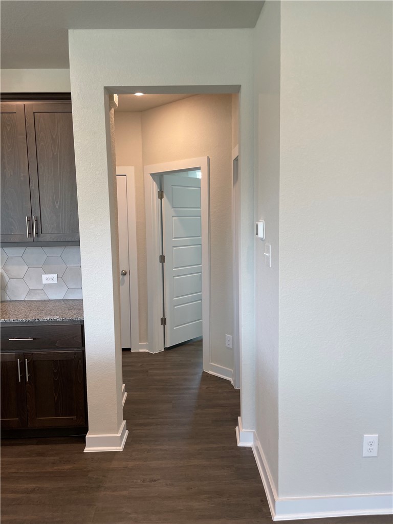 609 Paddock Lane Georgetown, TX 78626 - Photo 19 of 40 Rich wood cabinetry and stone counters transition seamlessly into a modern hallway with recessed lighting.