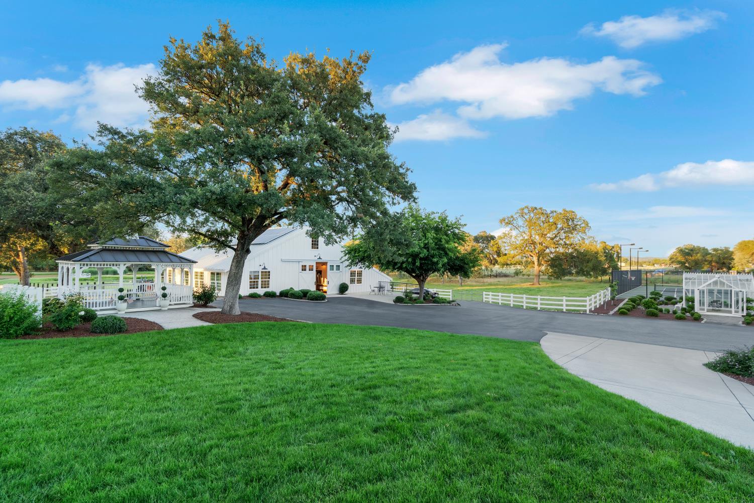 2905 Virginiatown Road Lincoln, CA 95648 - Photo 56 of 86 Expansive exterior featuring a white farmhouse-style building, a white gazebo with dark roof, a tennis court, and a greenhouse structure