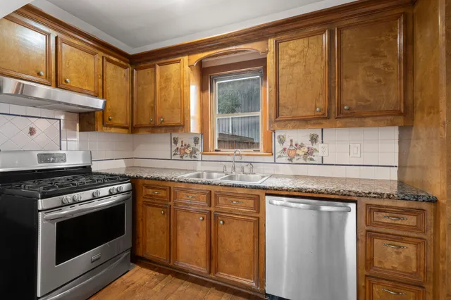 a kitchen with granite countertop cabinets stainless steel appliances and a sink