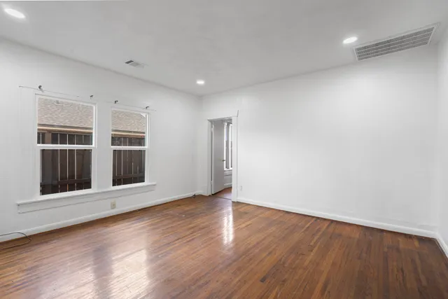 a view of an empty room with wooden floor and windows