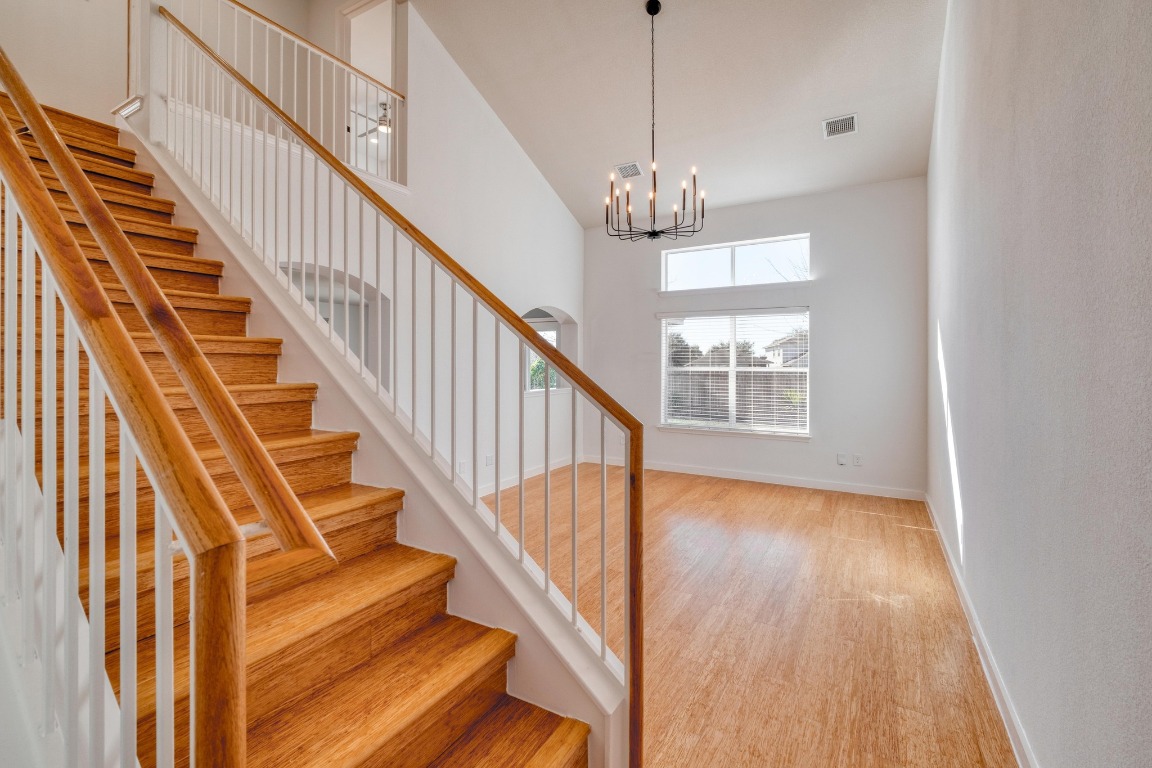 12825 James Madison Street Manor, TX 78653 - Photo 4 of 24 a view of staircase with wooden floor and a chandelier