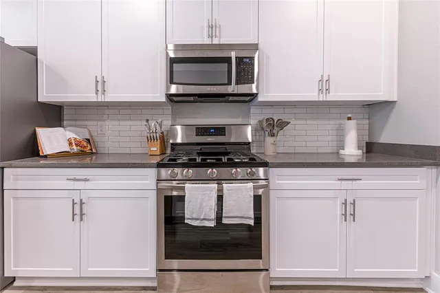 a kitchen with granite countertop white cabinets and stainless steel appliances