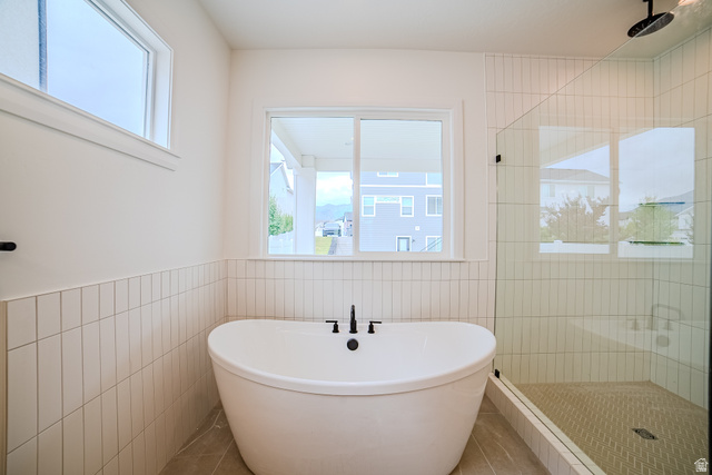 223 South Cottonwood Road, Unit 7501 Vineyard, UT 84059 - Photo 30 of 45 Freestanding soaking tub with matte black fixtures, framed by vertical stacked tile wainscoting