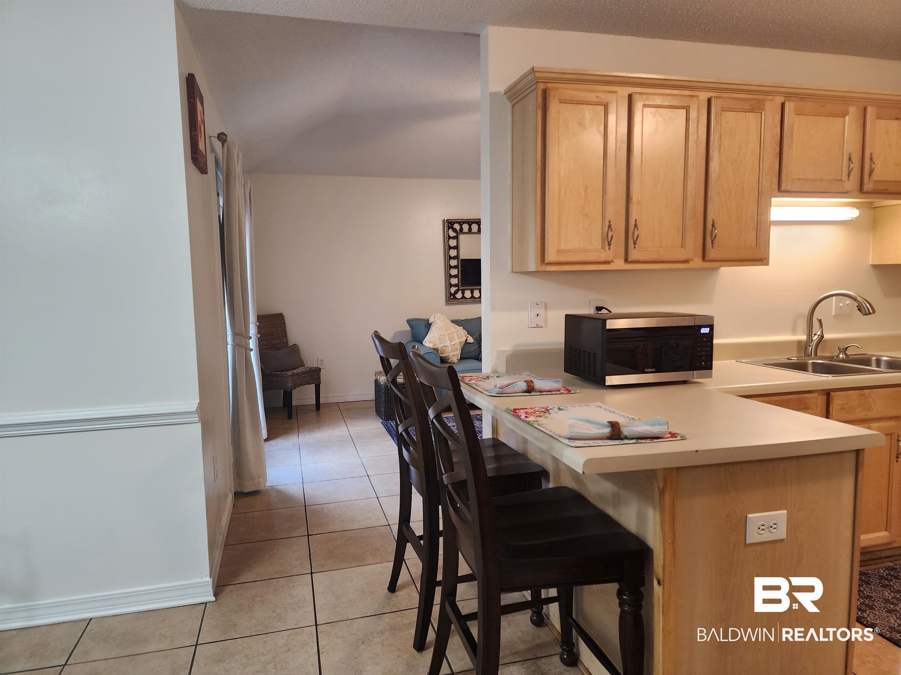 431 Hamilton Boulevard Foley, AL 36535 - Photo 21 of 30 Interior space with kitchen peninsula, breakfast bar, light tile patterned flooring, and sink/wood cabinets.