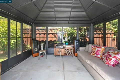 a view of a patio with couches chairs potted plants and wooden fence