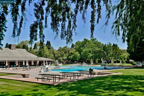 a view of a white house with a large windows and a table and chairs under an umbrella
