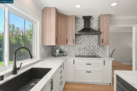 a large kitchen with kitchen island a large window cabinets and stainless steel appliances