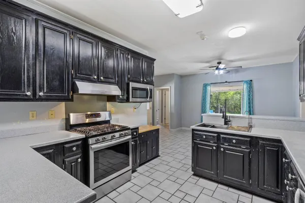 a kitchen with kitchen island granite countertop a sink stainless steel appliances and cabinets