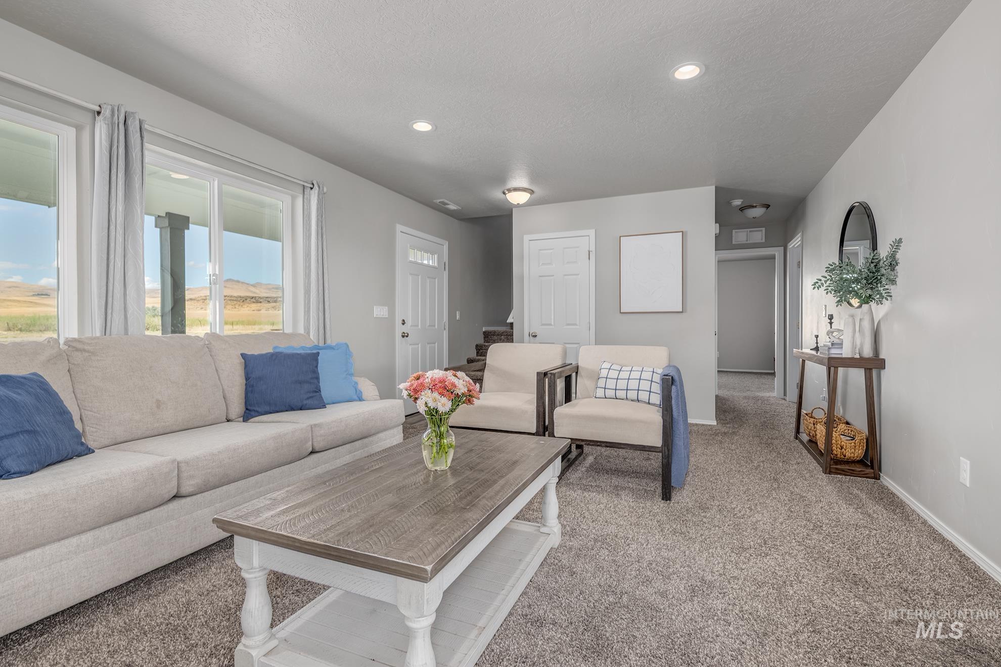 1049 Price Road Weiser, ID 83672 - Photo 4 of 47 Living area featuring light gray wall paint, gray carpeting, recessed ceiling lighting, and large sliding glass doors opening to outdoor scenery
