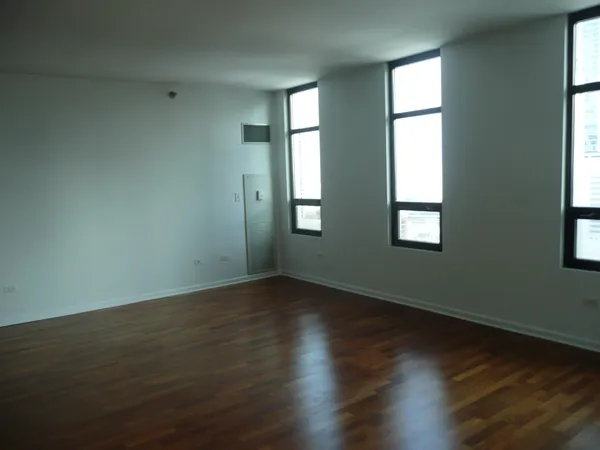 an empty room that has wooden floor and windows
