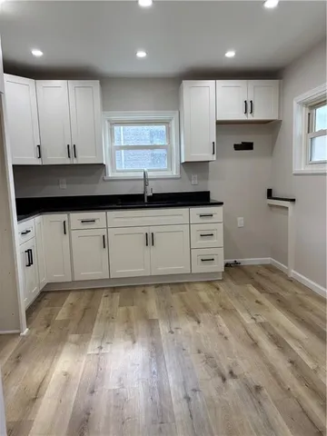 a kitchen with granite countertop a sink cabinets and wooden floor