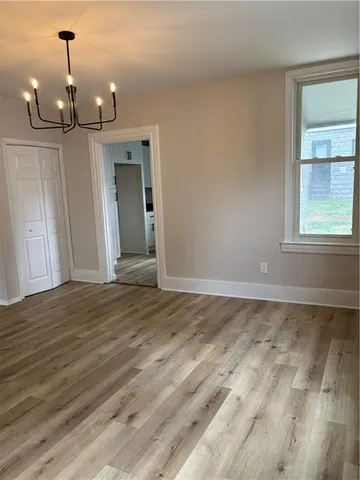 a view of an empty room with window and wooden floor