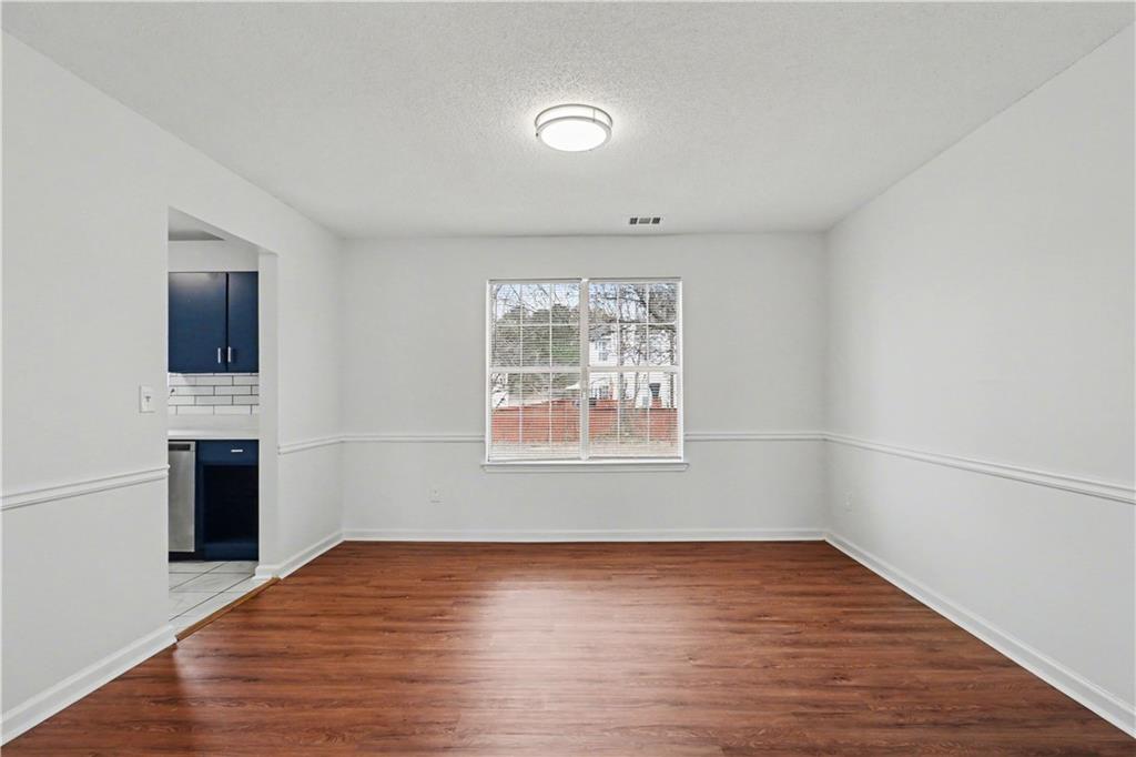 6236 Springwater Lane Lithonia, GA 30058 - Photo 6 of 23 an empty room with wooden floor cabinet and windows