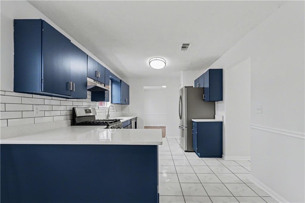 6236 Springwater Lane Lithonia, GA 30058 - Photo 7 of 23 a kitchen with stainless steel appliances a sink a stove a microwave a sink a refrigerator and cabinets