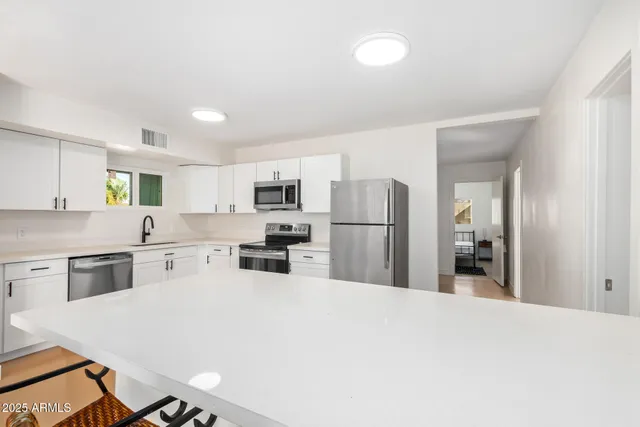 a kitchen with stainless steel appliances a refrigerator sink and white cabinets