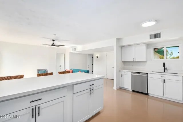 a kitchen with a sink dishwasher a stove and white cabinets with wooden floor