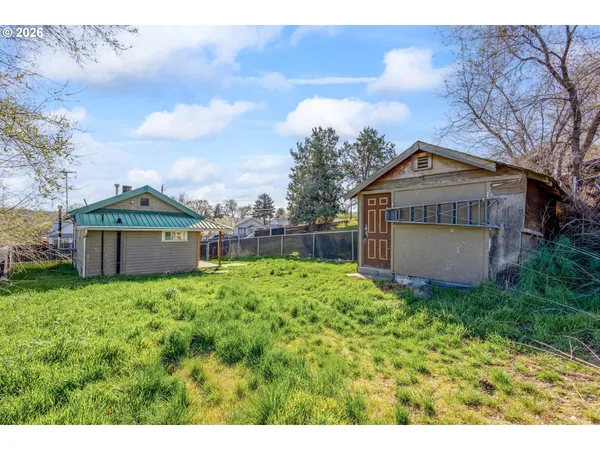 a view of a house with a yard and a large tree