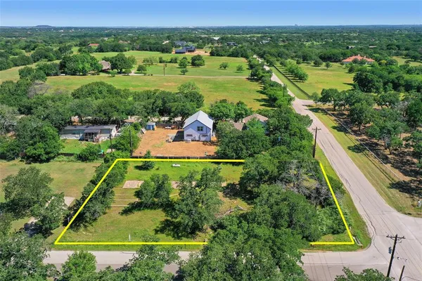 an aerial view of green landscape with trees houses and grass