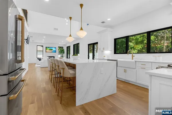 a large white kitchen with lots of counter space a sink appliances and a large window