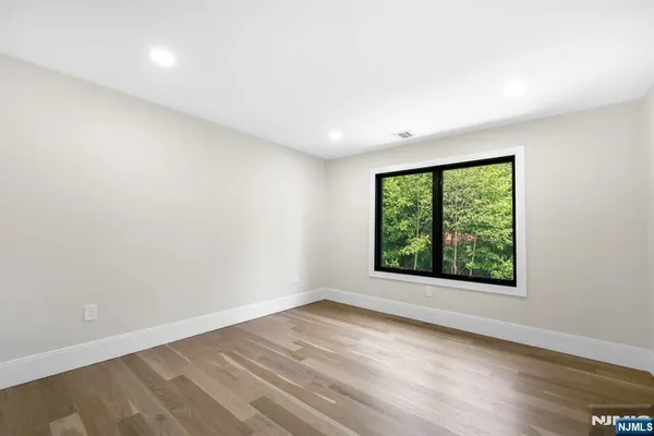 an empty room with wooden floor and entrance to ceiling window