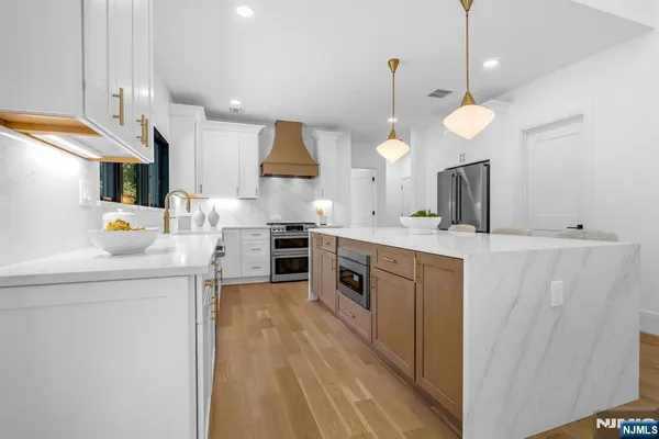 a kitchen with stainless steel appliances a refrigerator a sink dishwasher a oven and a dining table with wooden floor