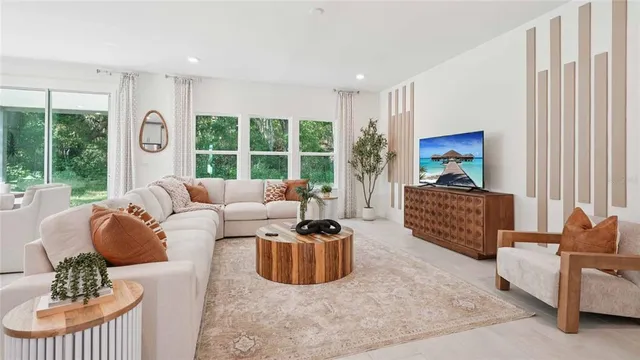 a living room with furniture floor to ceiling window and a flat screen tv