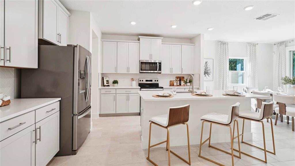 11269 Duckling Way Weeki Wachee, FL 34613 - Photo 7 of 33 a kitchen with white cabinets and stainless steel appliances
