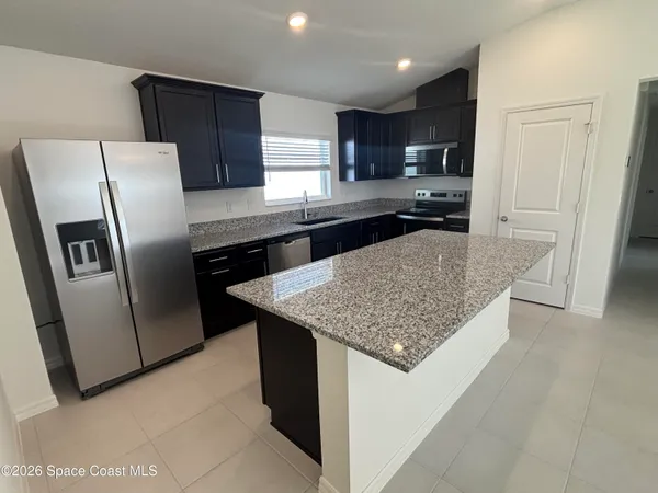 a kitchen with stainless steel appliances granite countertop a refrigerator a sink a stove a microwave and island