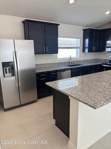 a kitchen with granite countertop a refrigerator a sink and wooden cabinets